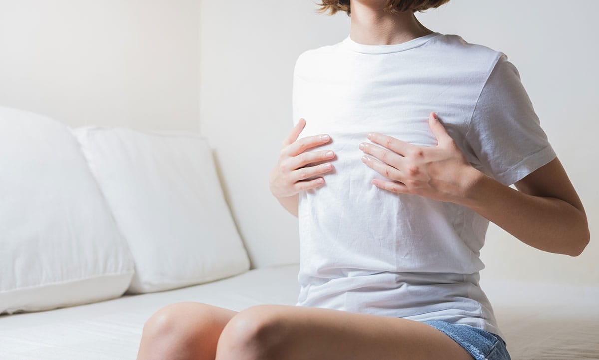 Woman holding her breast, representing concerns about breast animation deformity and treatment options at New York Group for Plastic Surgery.